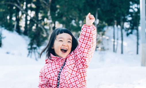 雪山で雪遊びをする4、5歳の女の子